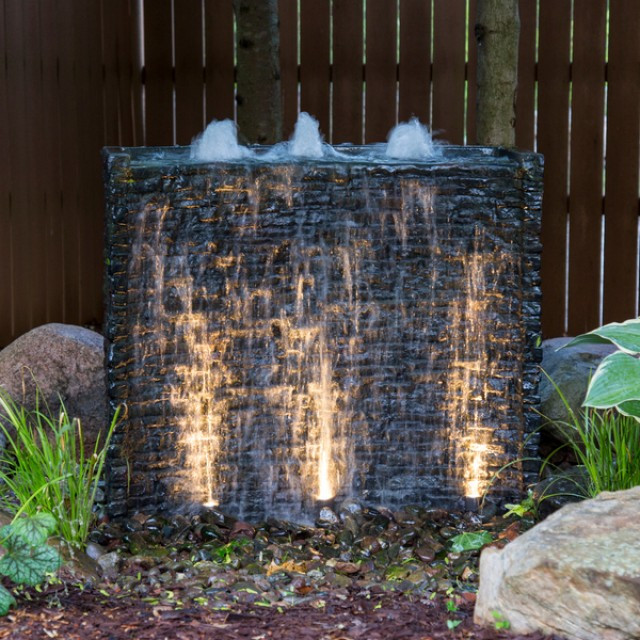 Illuminated stone wall water feature at night