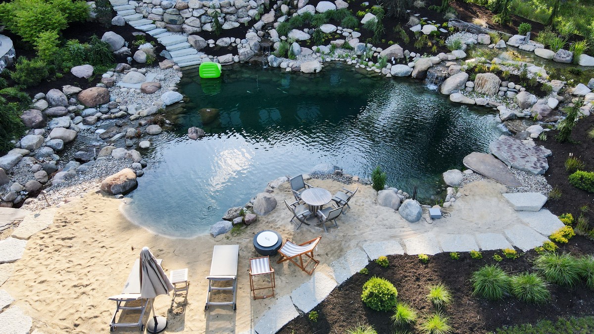 Drone aerial view of natural swim pond with sandy beach entry