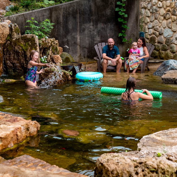 Family swimming in natural ecosystem pond