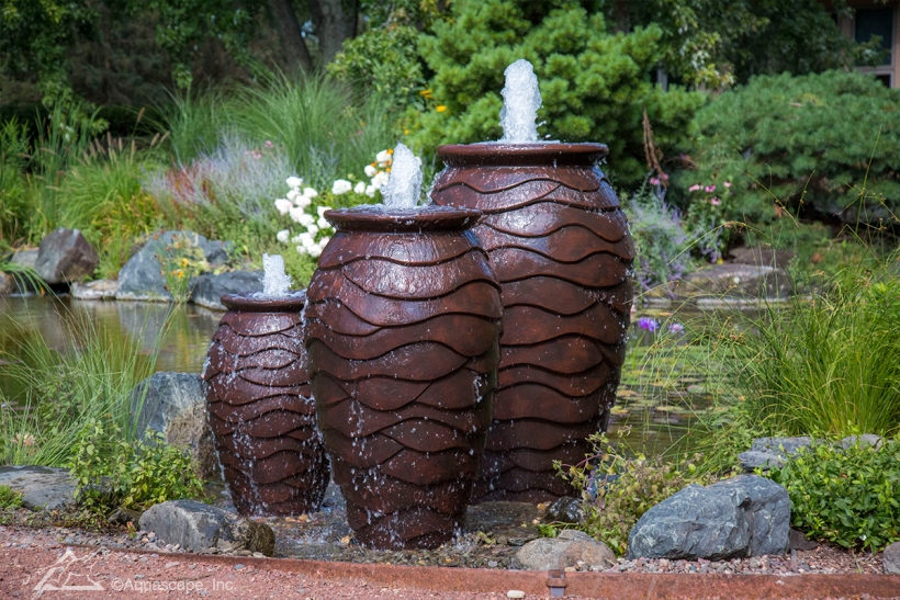 Three decorative urn fountains in a garden setting